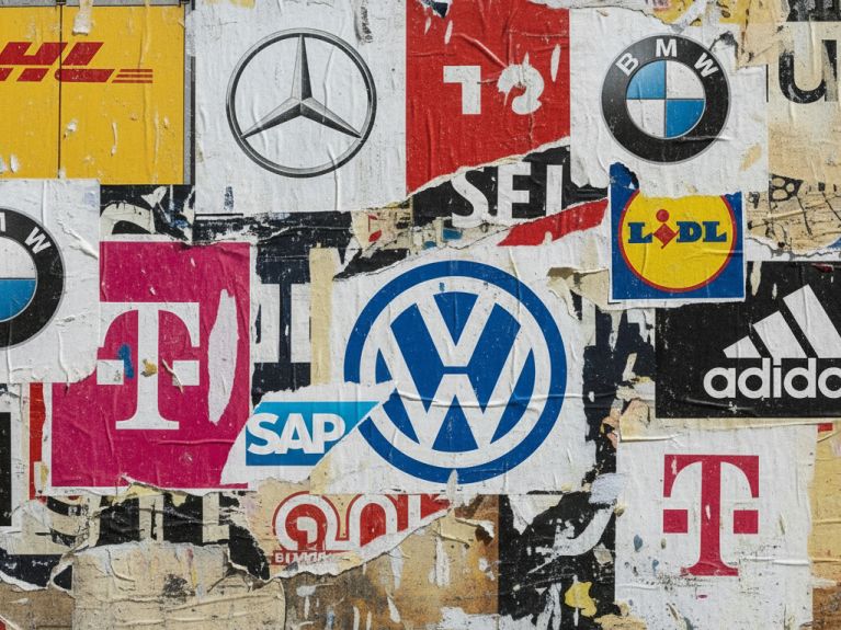 Fotocollage mit auf einer Wand klebenden Schnipseln, die Logos deutscher Marken zeigen