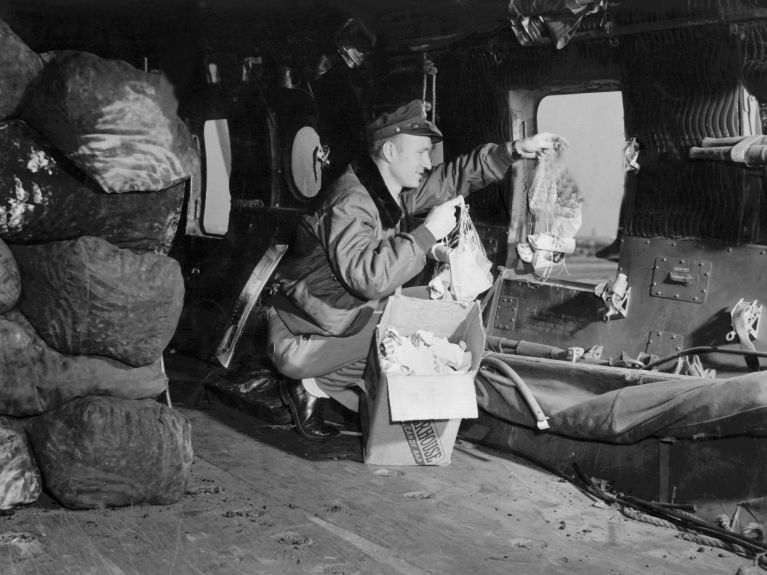 70 ans de pont aérien berlinois : Le lieutenant américain Gail Halvorsen jette des sucreries aux enfants à l’aide de petits parachutes. 