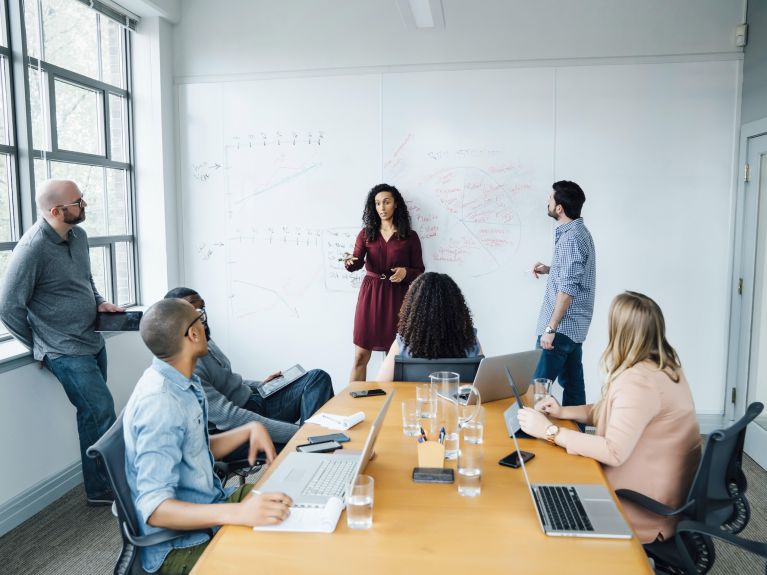 Personen sitzen und stehen in einem Büro.