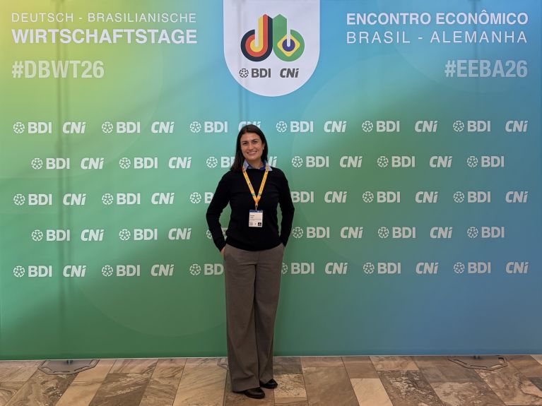 Eine junge Frau vor einem Banner der Deutsch-Brasilianischen Wirtschaftstage
