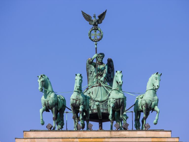 Die Quadriga-Skulptur zeigt die römische Siegesgöttin Victoria auf einem von vier Pferden gezogenen Streitwagen. Die Quadriga-Skulptur zeigt die römische Siegesgöttin Victoria auf einem von vier Pferden gezogenen Streitwagen.