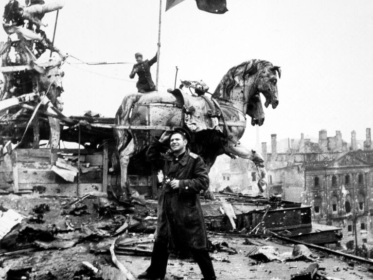 Rotarmisten hissen am 2. Mai 1945 vor der zerstörten Quadriga eine Rote Fahne zum Zeichen des Sieges über den Nationalsozialismus. Rotarmisten hissen am 2. Mai 1945 vor der zerstörten Quadriga eine Rote Fahne zum Zeichen des Sieges über den Nationalsozialismus.
