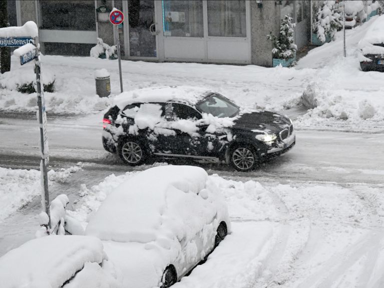 Un coche circula entre montones de nieve por un cruce en Múnich.