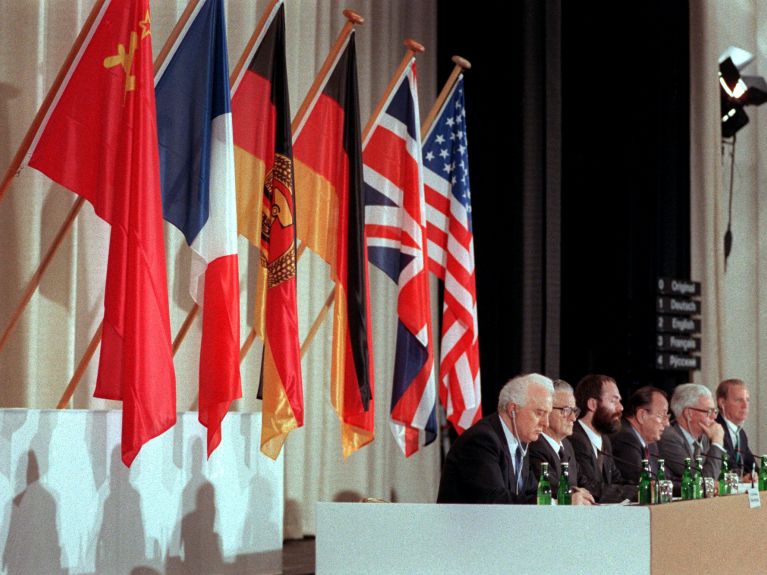 The representatives of the Two Plus Four countries in front of their flags. 