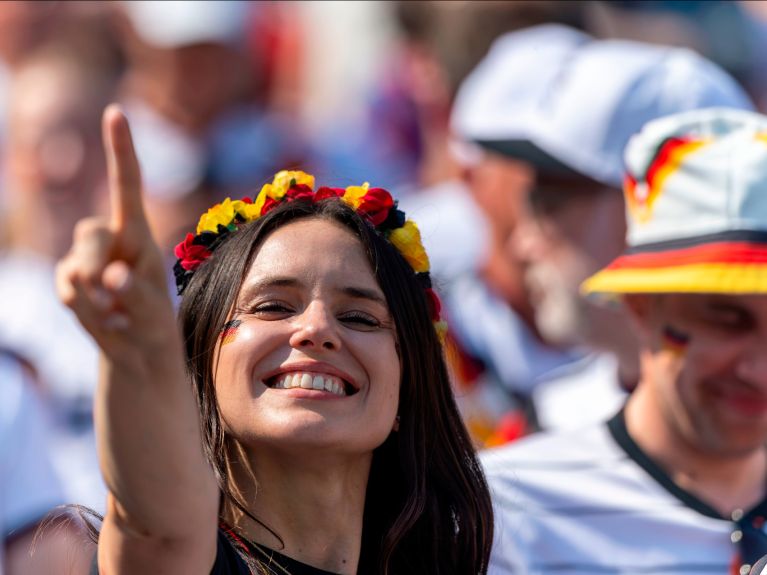Smiling woman wearing a black, red and gold floral wreath in her hair