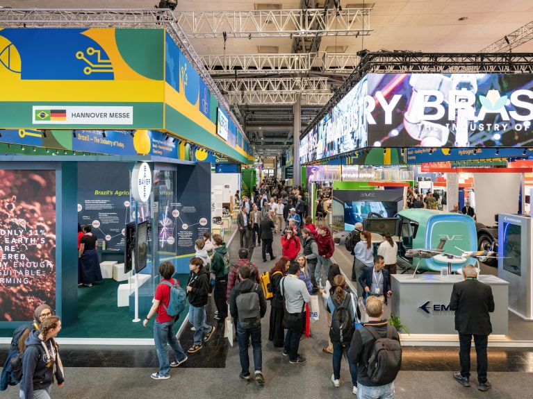 Blick in eine Messehalle, an vielen Stellen sind die brasilianischen Nationalfarben zu sehen.