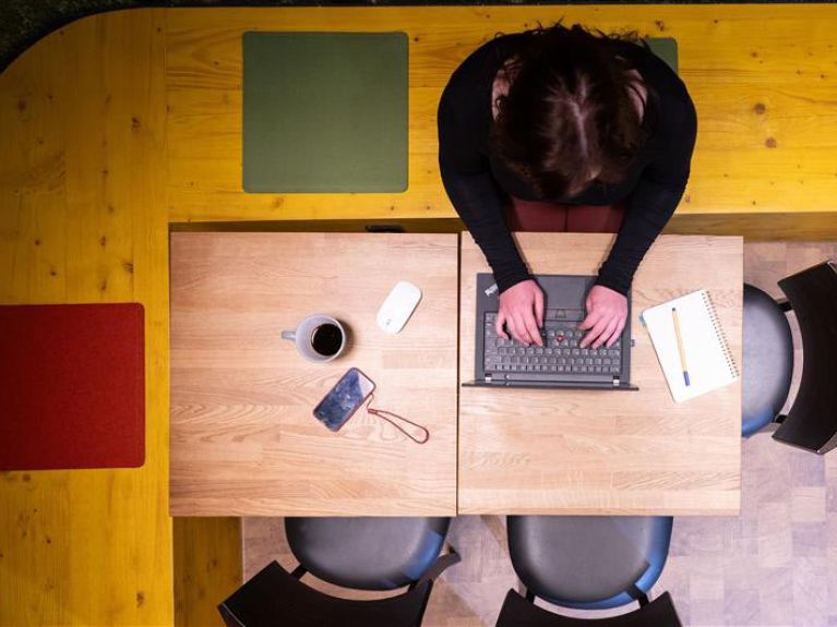 Eine Frau sitzt am Schreibtisch am Laptop. 