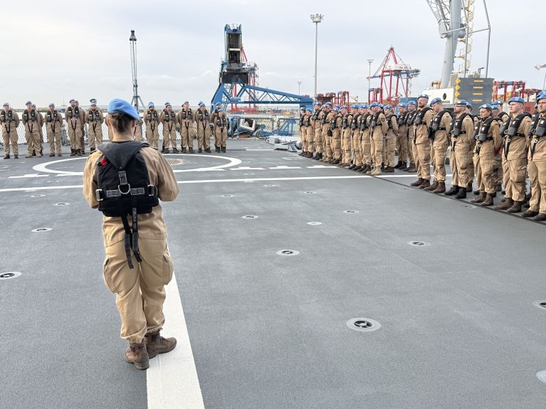 A number of Bundeswehr soldiers are standing on the deck of a ship. 