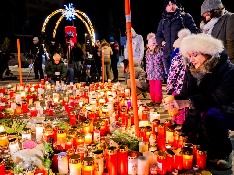 Menschen zollen den Opfern mit Blumen und Kerzen ihren Respekt.