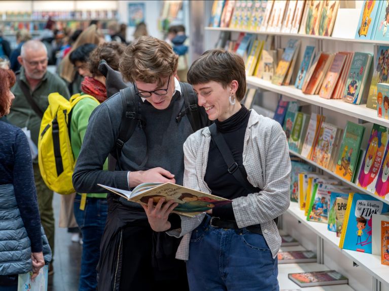 Two people look at a children’s book.