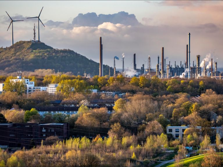 Industrial landscape with refinery facilities, tall chimneys and rising steam 