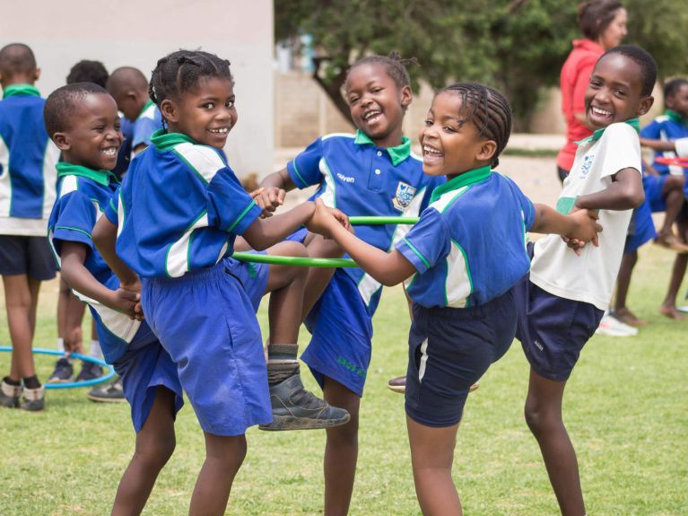 فتيانٌ وفتيات يمارسون الرياضةَ معًا في مدرسةٍ في ناميبيا.  