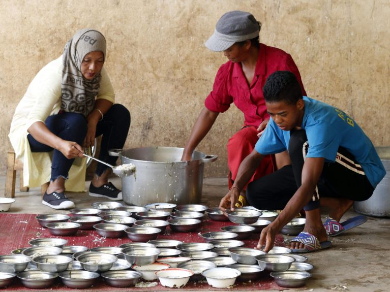 Os ajudantes preparam alimentos para os famintos. 