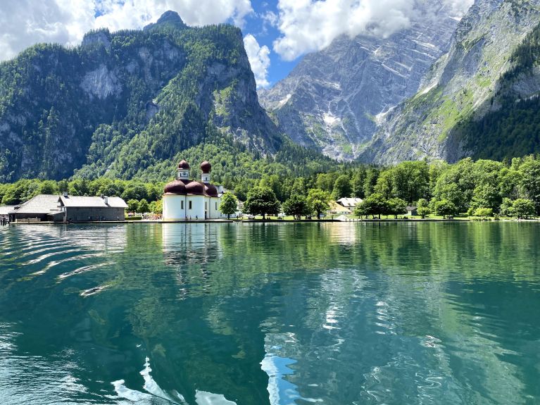     Kristallklarer See, malerische Kapelle: Am Königsee liegt die Wallfahrtskapelle St. Bartholomä, die mit roten Zwiebeltürmen und Kuppeldächern geschmückt ist.  