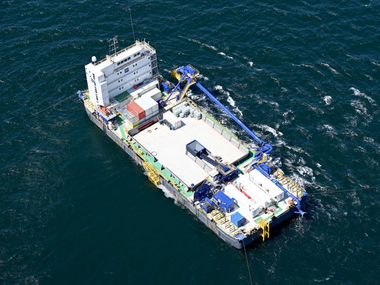 El pontón esparcidor cubre los laterales de la zanja del túnel con arena y grava.