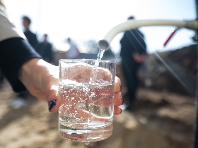 Wasser fließt aus einem Hahn in ein Glas.