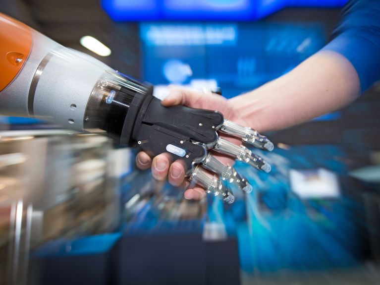Digitalização do mundo do trabalho: o homem e o robô trabalham de mãos dadas.