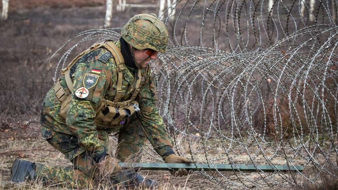 Ein Soldat der Pioniertruppe errichtet eine Drahtsperre, um gegnerische Kräfte aufzuhalten.