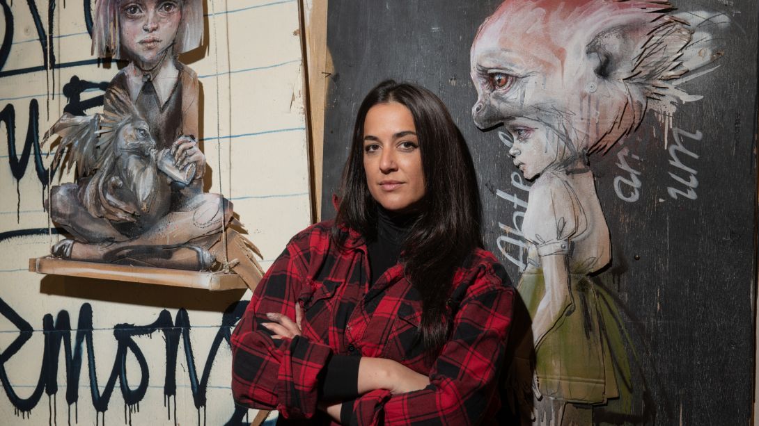 Graffiti-Künstlerin Hera vor einer Wand mit ihrer Kunst