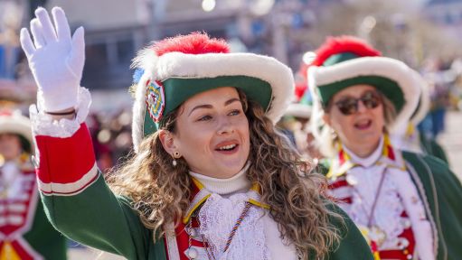 Eine Gardistin mit Hut hebt winkend die Hand. 