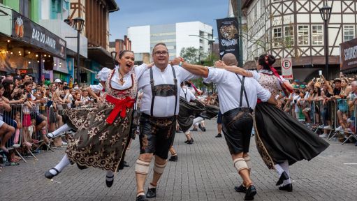Paare in Trachten und Lederhosen tanzen beim Oktoberfest in Blumenau.