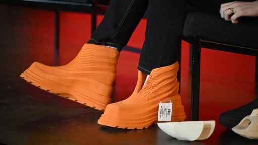 Eine Person trägt leuchtend orange Schuhe. 
