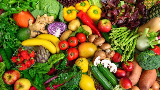 Verschiedene bunte Gemüse- und Obstsorten liegen dich nebeneinander drapiert.