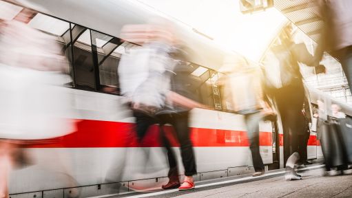 Mehrere Menschen welche unscharf vor einem Zug laufen