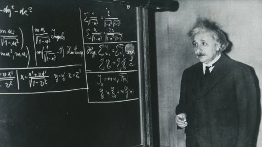 Albert Einstein steht an einer Tafel.