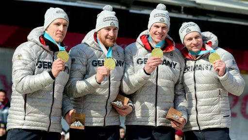 Vier deutsche Wintersportler halten ihre Goldmedaille hoch.