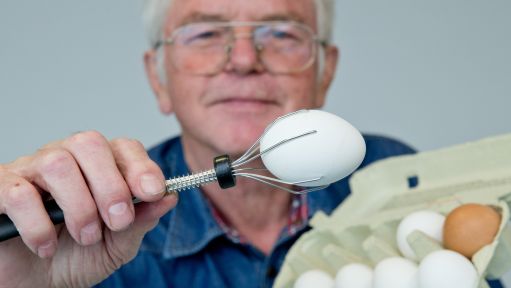 Ein Mann hält ein Ei mit einem Eierhalter in der Hand