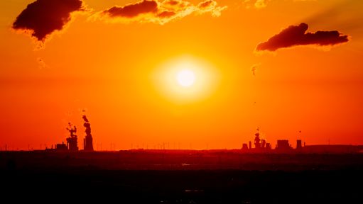 Sonnenuntergang in kräftigen Orangetönen über einer Industrielandschaft. 