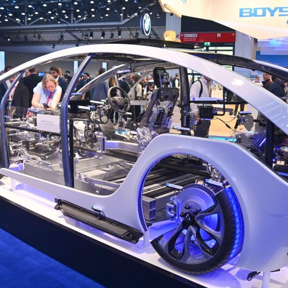 Auf einer Automobilmesse betrachten Besucher ein Auto ohne Karosserie. 