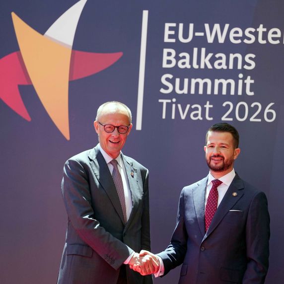 Bundeskanzler Friedrich Merz und Jakov Milatovic, Präsident von Montenegro, geben sich die Hand. Sie stehen vor einem Plakat mit der Aufschrift „EU Western Balkans Summit Tivat 2026“. 
