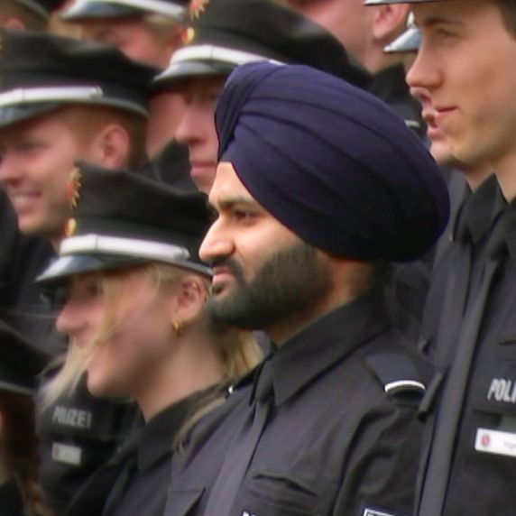 Mehrere junge Männer und Frauen in Polizeiuniform stehen auf  einer Treppe. Einer der Männer trägt einen Turban.