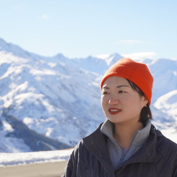 Junge Chinesin vor hohen schneebedeckten Bergen