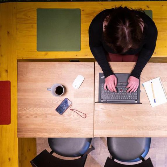 Eine Frau sitzt am Schreibtisch am Laptop. 
