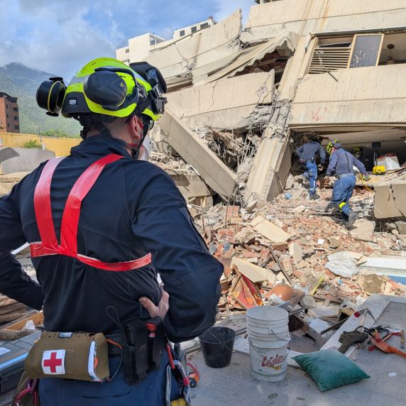 Ein Mann mit Schutzhelm steht vor einem eingestürzten Gebäude