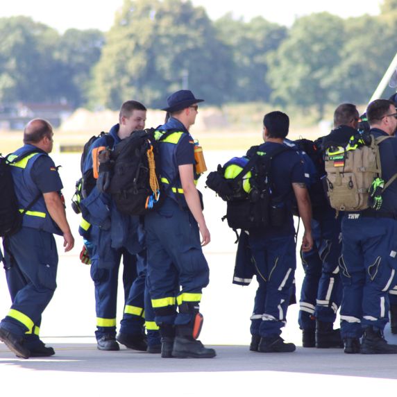 Einsatzkräfte des Technischen Hilfswerks steigen in ein Transportflugzeug.