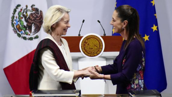Zwei Frauen stehen sich gegenüber und halten einander an den Händen. 