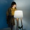 Brunette little girl in yellow knitted sweater and leopard skirt standing on a backseat of a couch at home. She's looking at dim night light from above. Her face is lit. 