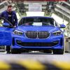 Ein Firmenmitarbeiter stehet neben einem blauen BMW 1er, der im BMW Group Werk Leipzig vom Band läuft.