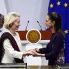 Zwei Frauen stehen sich gegenüber und halten einander an den Händen. 