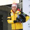 Portrait der deutschen Bobfahrerin Laura Nolte. Sie trägt die offizielle Kleidung des deutschen Wintersportteams und hält ihren Bob-Helm unter dem Arm.