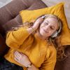 Eine junge Frau liegt mit geschlossenen Augen und Kopfhörern auf einem Sofa