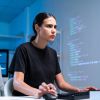 Eine junge Frau betrachtet konzentriert einen Computerbildschirm.