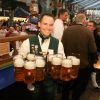 Ein Mann hält 12 Maß Bier in der Hand und lächelt