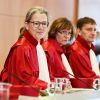 Drei Frauen und ein Mann in roten Roben sitzen an einem Tisch.