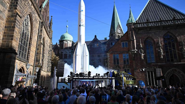 Weißer Ariane-Raketennachbau auf einer Bühne vor historischen Gebäuden 