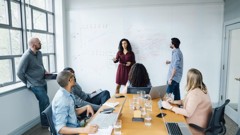 Personen sitzen und stehen in einem Büro.